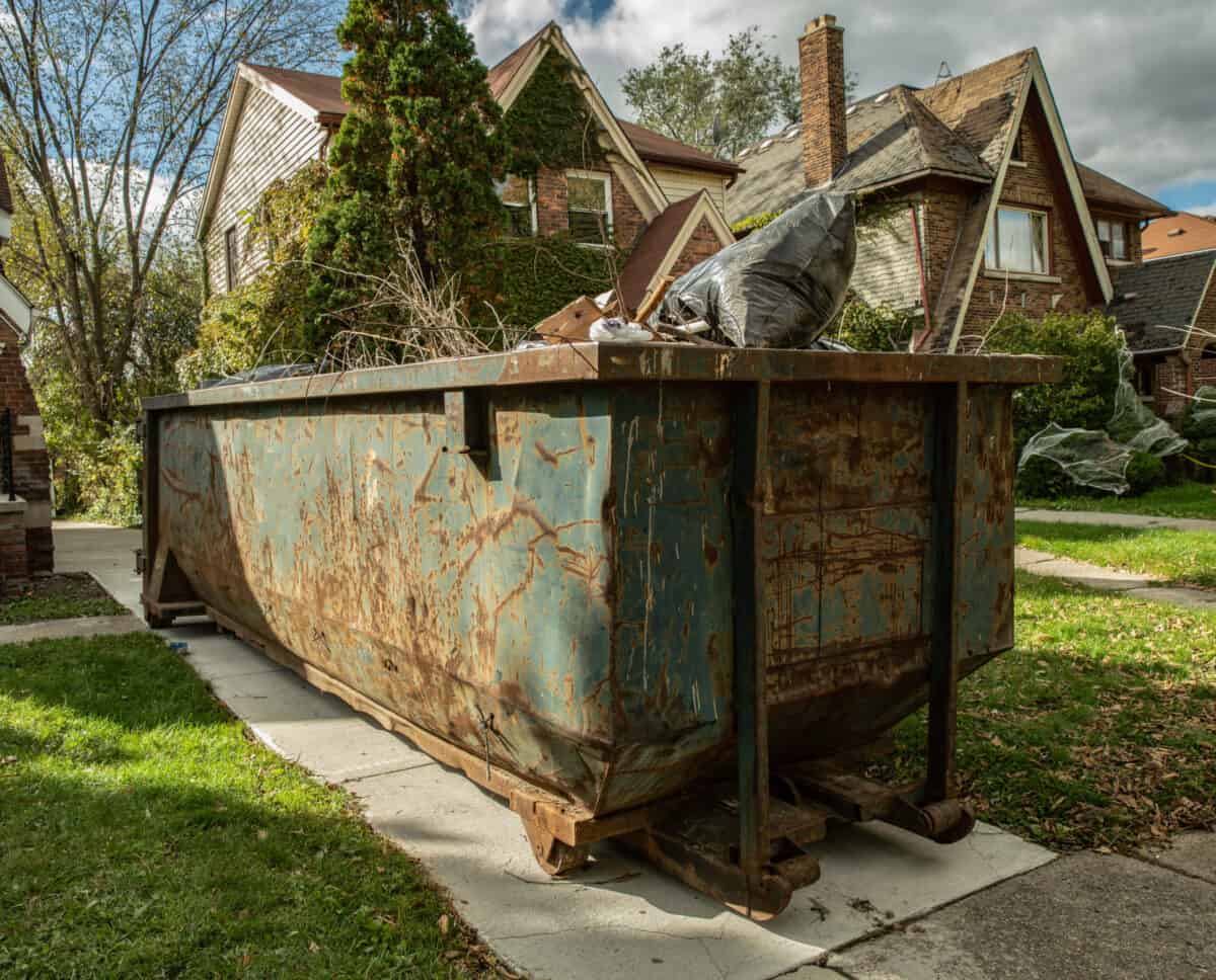 overloaded rusted dumpster in driveway