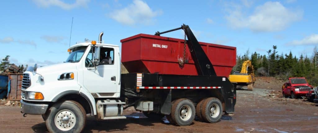 Dump truck transporting metal waste at a recycling facility in a rural area under clear skies