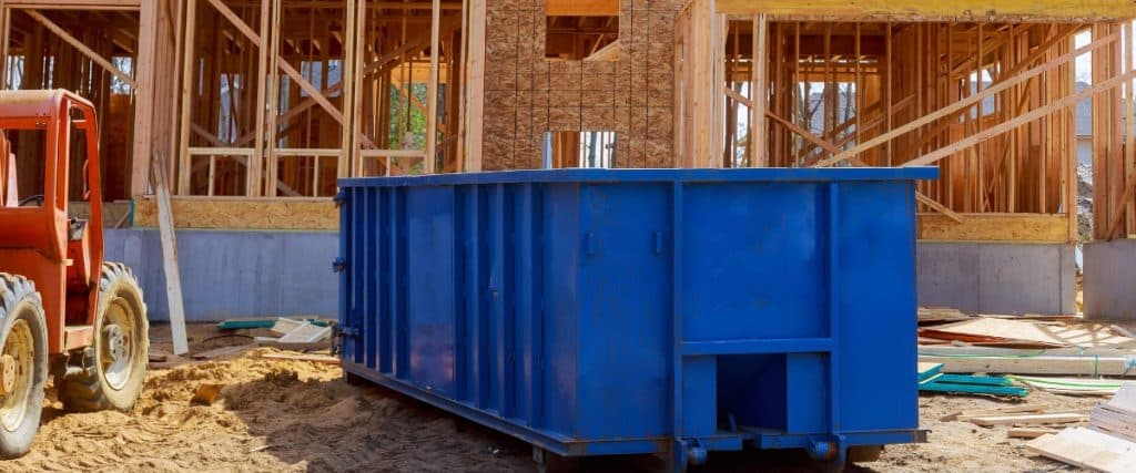 Construction site with blue dumpster and machinery during daylight hours