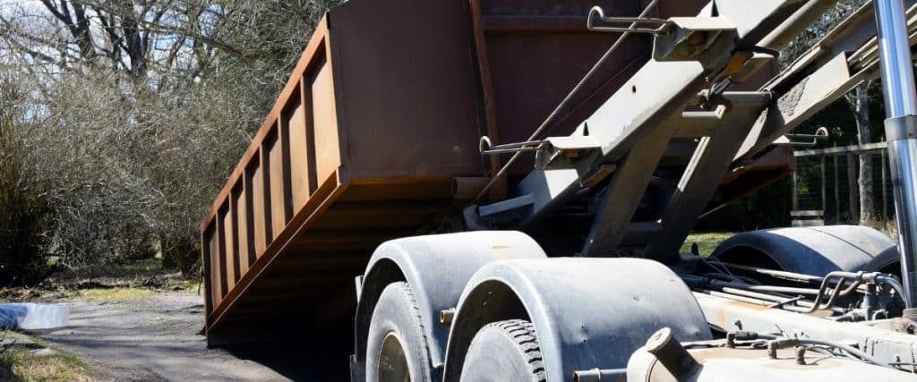 Heavy-duty truck unloading materials at a construction site during bright daytime