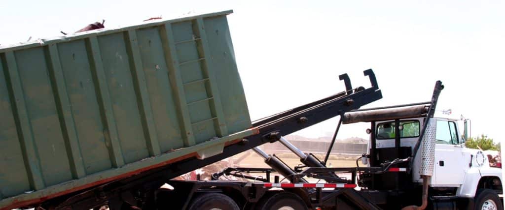 Truck unloading waste in a construction site during bright daylight under clear blue sky
