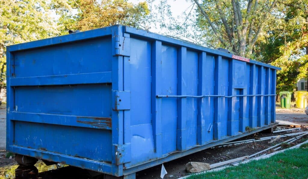 Large blue dumpster on grassy area