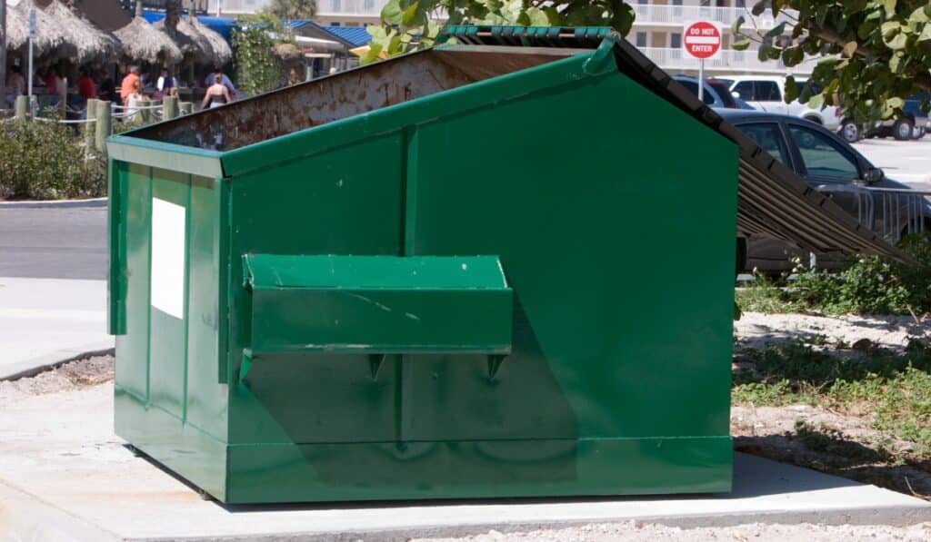 Green dumpster with slanted roof
