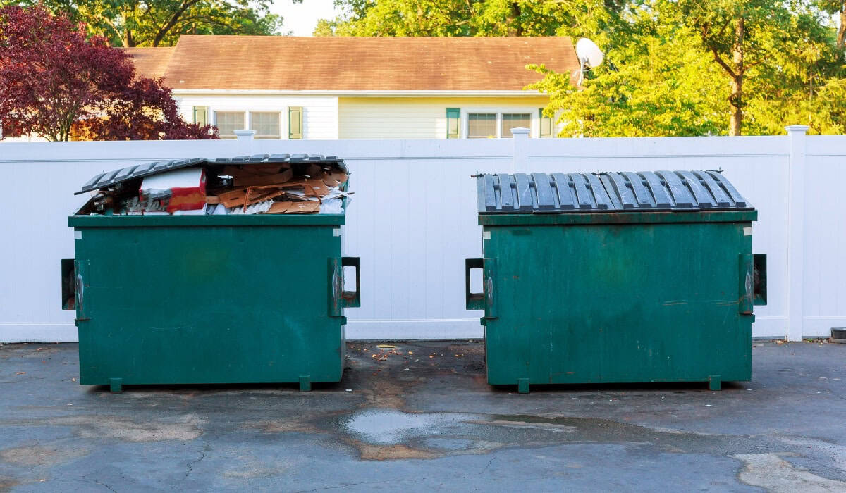Two green dumpsters filled with debris.