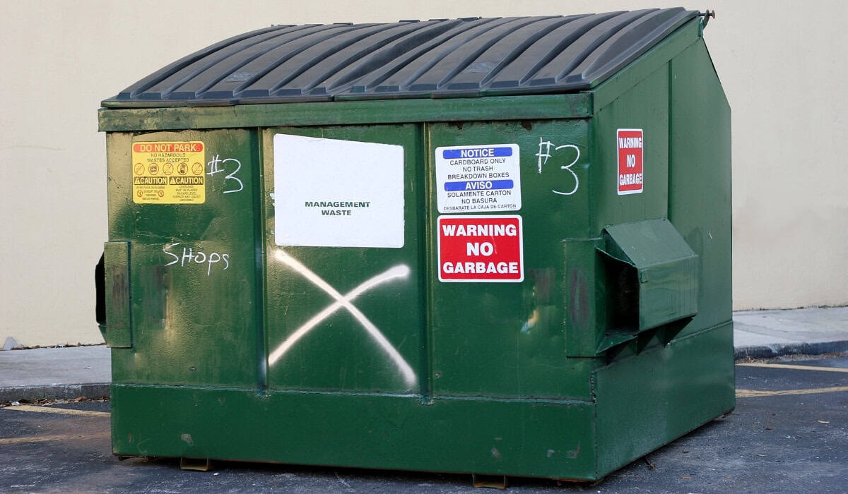 Green dumpster with warning signs.