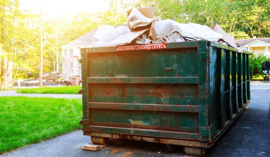 Overloaded dumpster with warning sign.