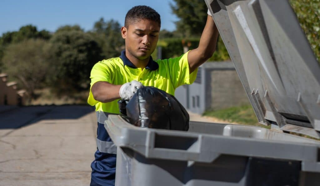 Person disposing of trash in dumpster.
