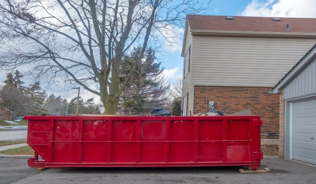 Large red dumpster beside a house